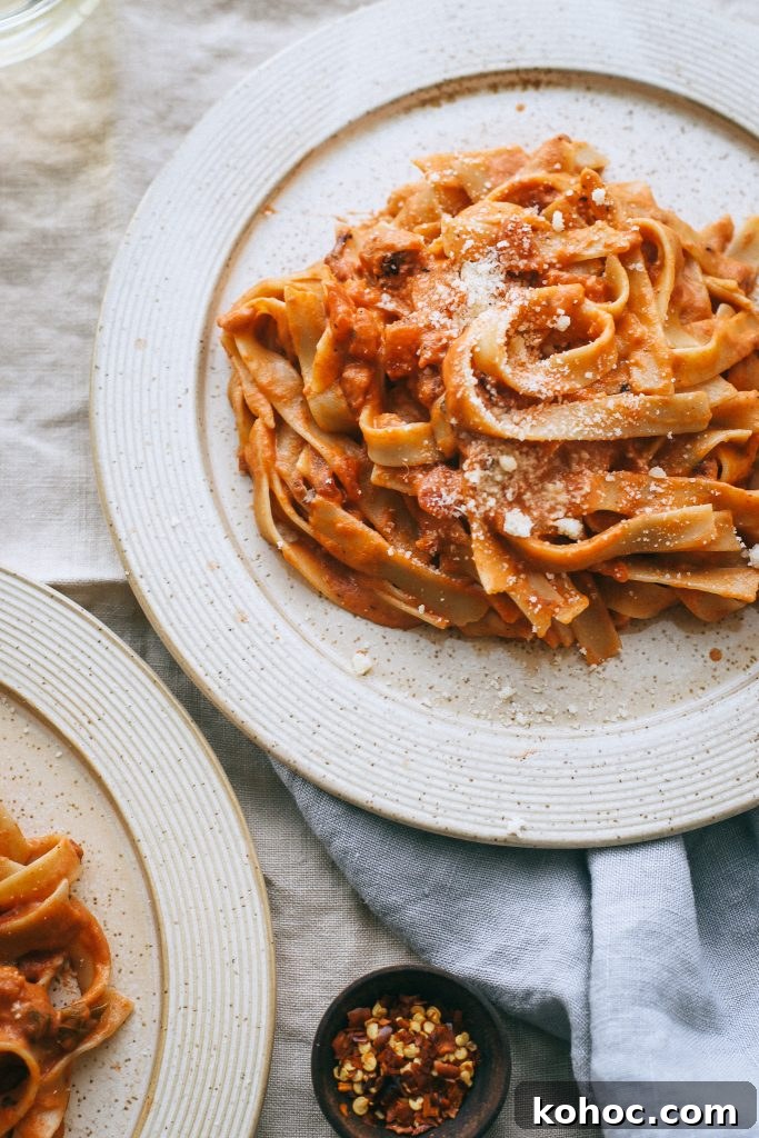 Grandma’s Classic Vodka Sauce Recipe برای Family Gatherings 2 vodka sauce pasta on pale yellow plate with small dish of red pepper flakes