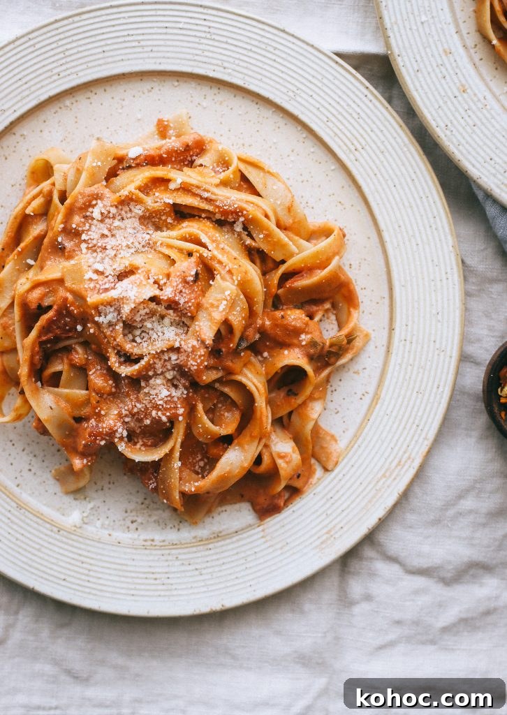 Grandma’s Classic Vodka Sauce Recipe برای Family Gatherings 5 vodka sauce pasta on pale yellow plate with small dish of red pepper flakes