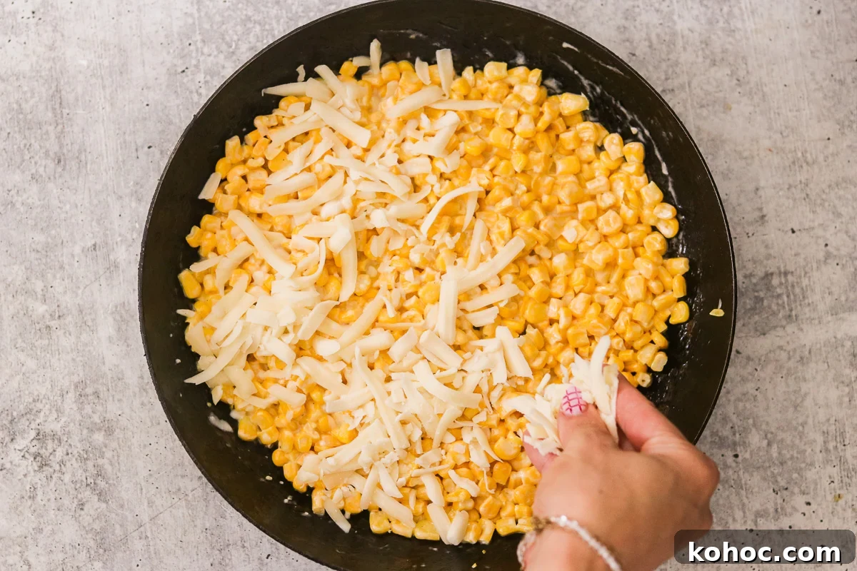 Korean Corn Cheese Recipe: Creamy Baked Koncheese for Sharing 6 Corn and mayo mixture flattened in a skillet and topped evenly with shredded mozzarella cheese before melting.