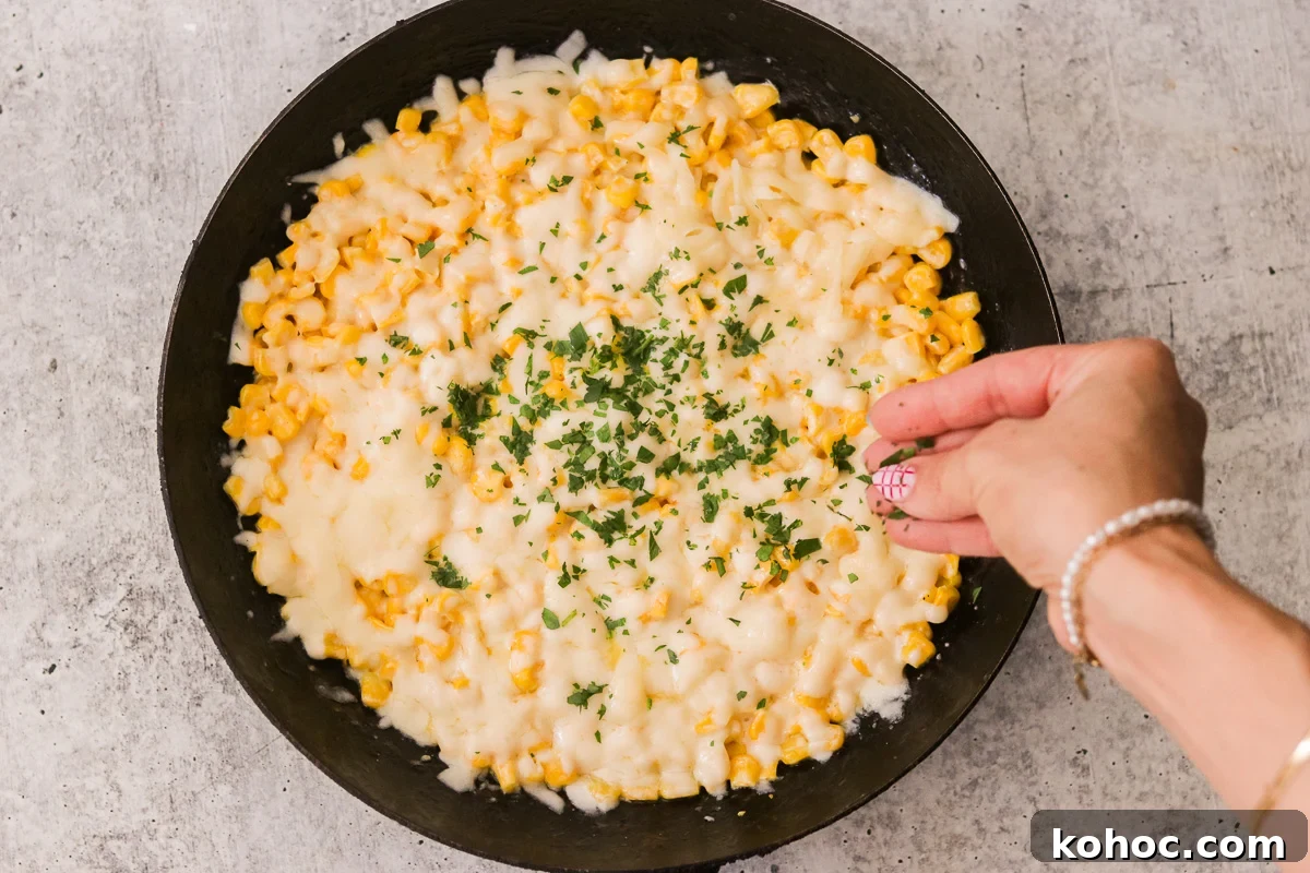 Korean Corn Cheese Recipe: Creamy Baked Koncheese for Sharing 7 Hot Korean corn cheese garnished with chopped parsley in a skillet, ready to serve.