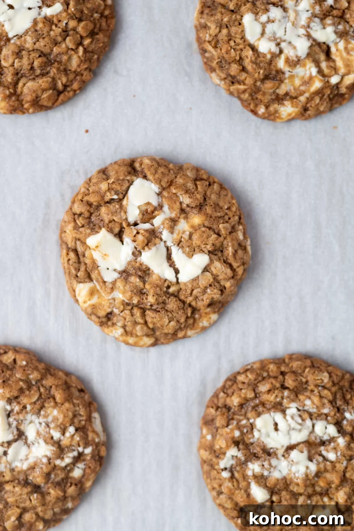 Chewy Brown-Butter Oatmeal Cookies with Sea Salt 8 baked cookies on a parchment lined baking sheet showing puddles of melted chocolate