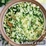overhead image of a cabbage green goddess salad in a white and brown bowl with gold salad tongs.