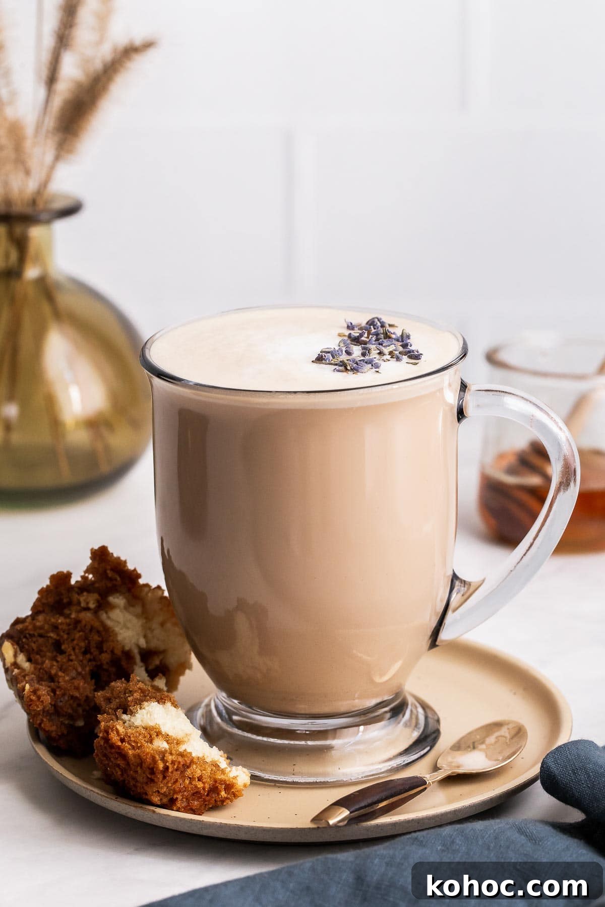 Starbucks London Fog Latte Copycat Recipe: How to Make It at Home 5 London fog tea latte in clear glass mug with lavender buds.