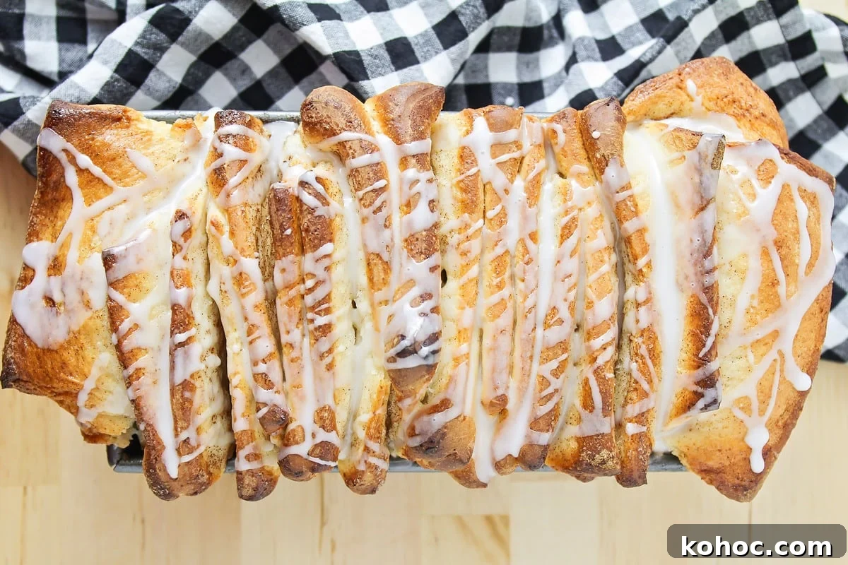 Cinnamon Roll Pull Apart Bread in a bread pan, drizzled with a glaze