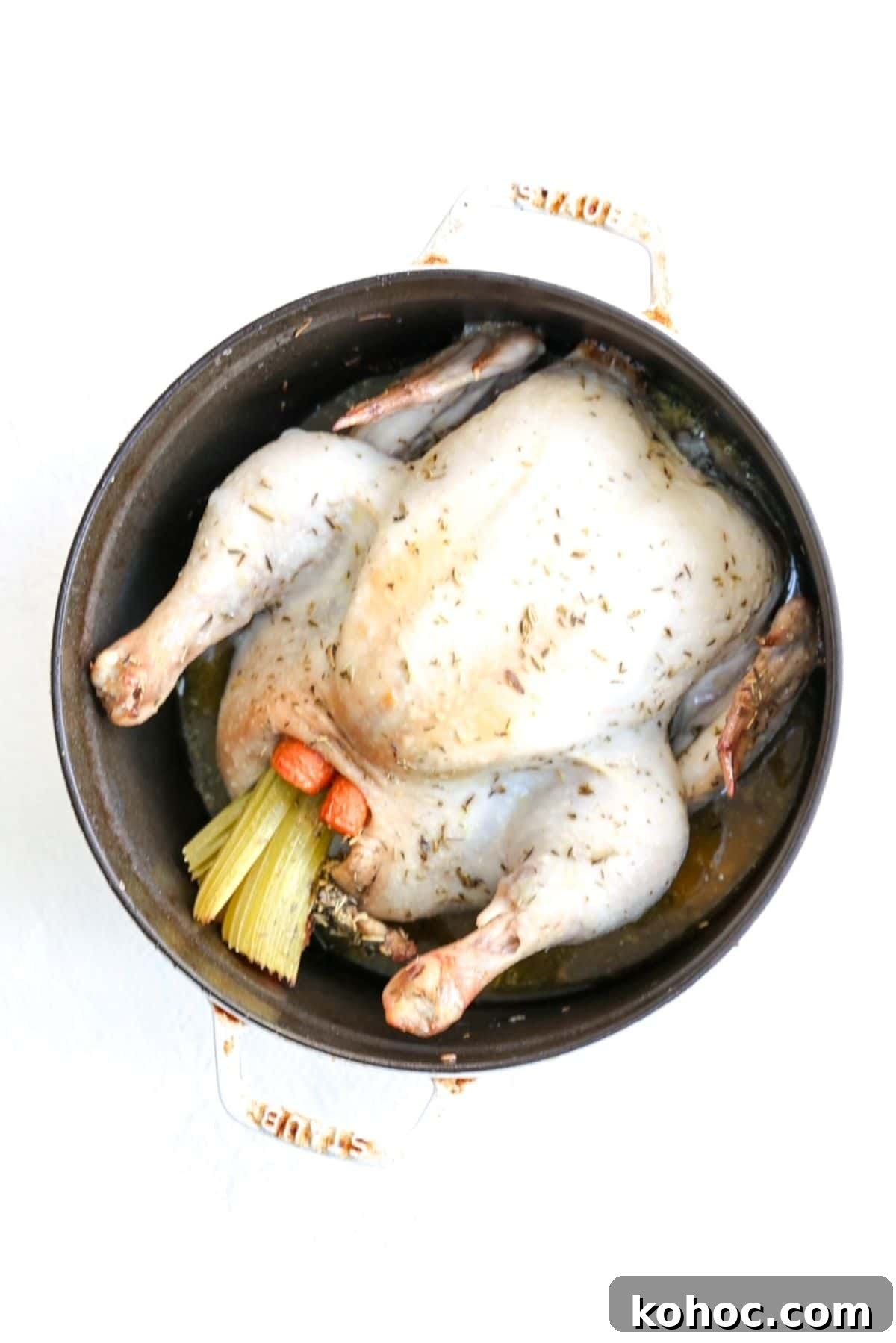 Dutch Oven Roast Chicken with Crispy Skin and Herb Pan Sauce 2 One whole roasted chicken stuffed with carrots and celery in a white Dutch oven.