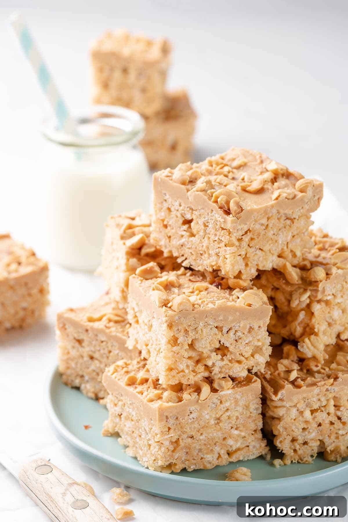 Peanut Butter Rice Krispie Treats Recipe — Chewy No-Bake Bars 2 stack of rice krispie treats on green plate with milk on the side