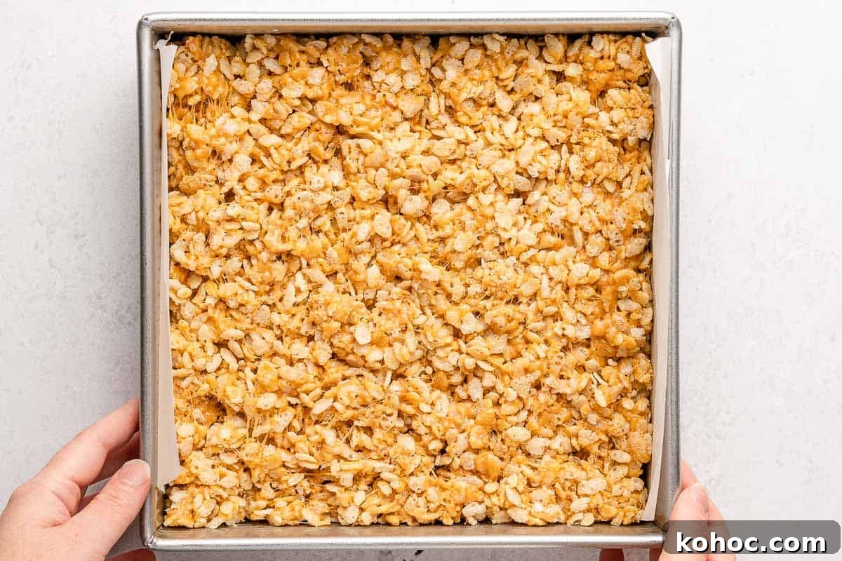 Peanut Butter Rice Krispie Treats Recipe — Chewy No-Bake Bars 4 hands holding square pan with rice krispie treats inside