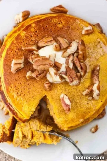 A stack of pumpkin pancakes topped with chopped pecans.