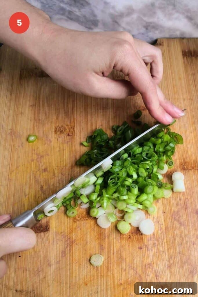 Juicy Chicken Poke Bowl Recipe for Fresh, Flavor-Packed Meals 8 Slicing scallions with a knife on a cutting board.