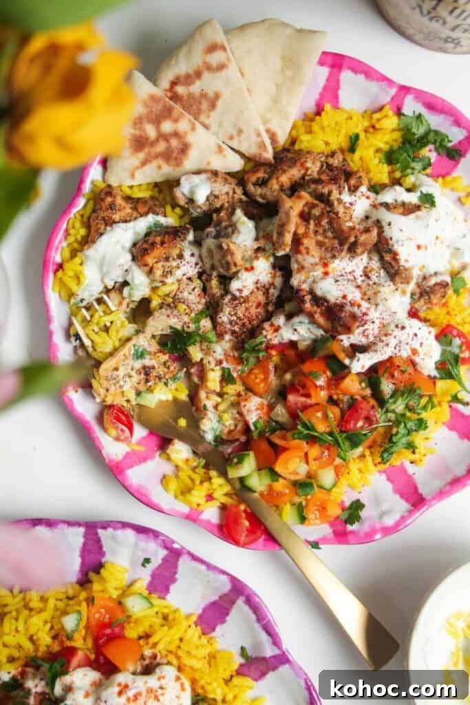 Juicy Chicken Poke Bowl Recipe for Fresh, Flavor-Packed Meals 10 Chicken, salad and rice on a pink and white striped plate with pita bread on the side.