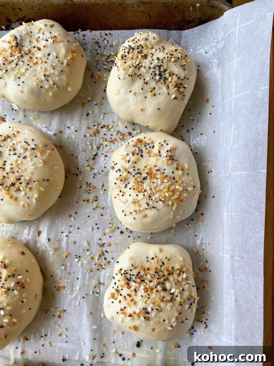 Stuffed dinner rolls with a sprinkling of everything bagel seasoning  top, placed on a baking sheet 