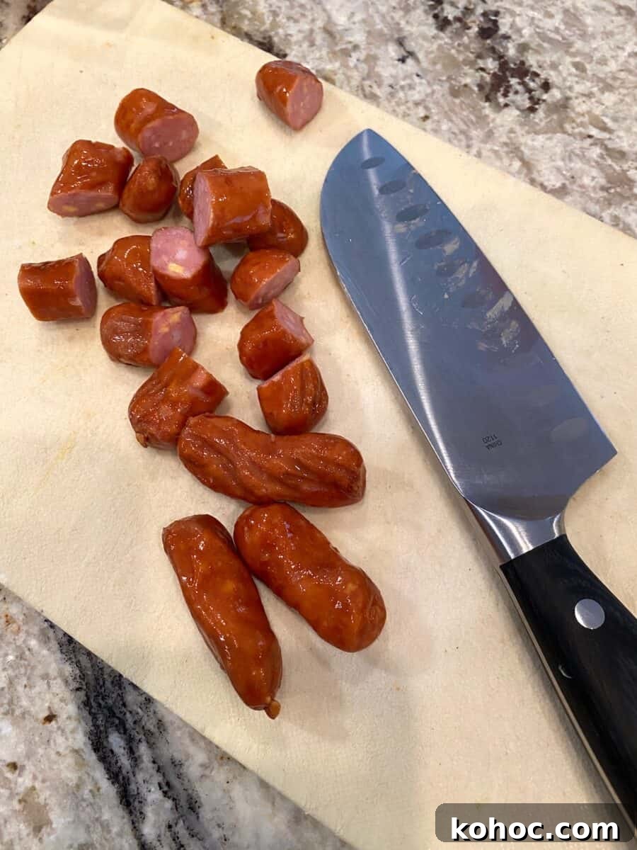 Diced little smokies on a small cutting board with a knife on the side