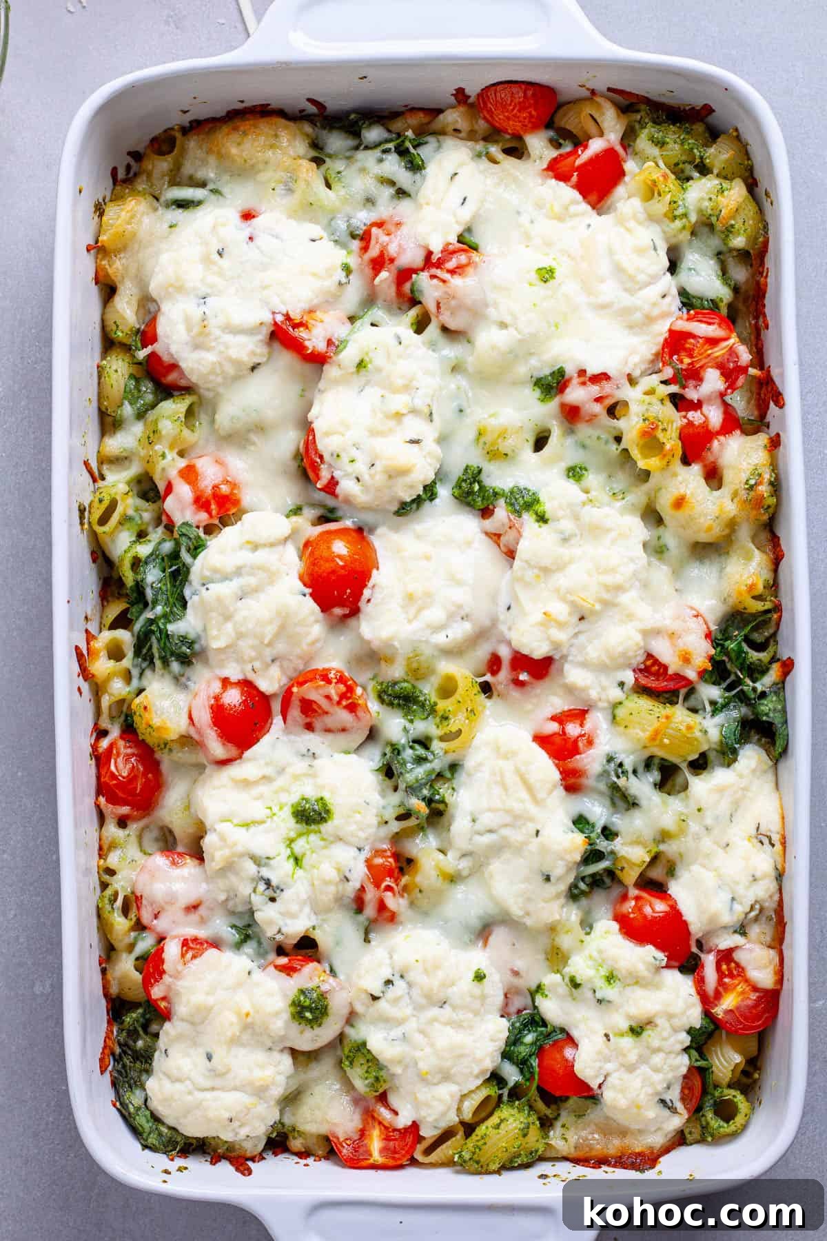 Creamy Baked Ricotta Pesto Pasta with Golden Parmesan Crust 11 A casserole dish of pesto and ricotta baked pasta hot out of the oven topped with tomatoes and spinach.