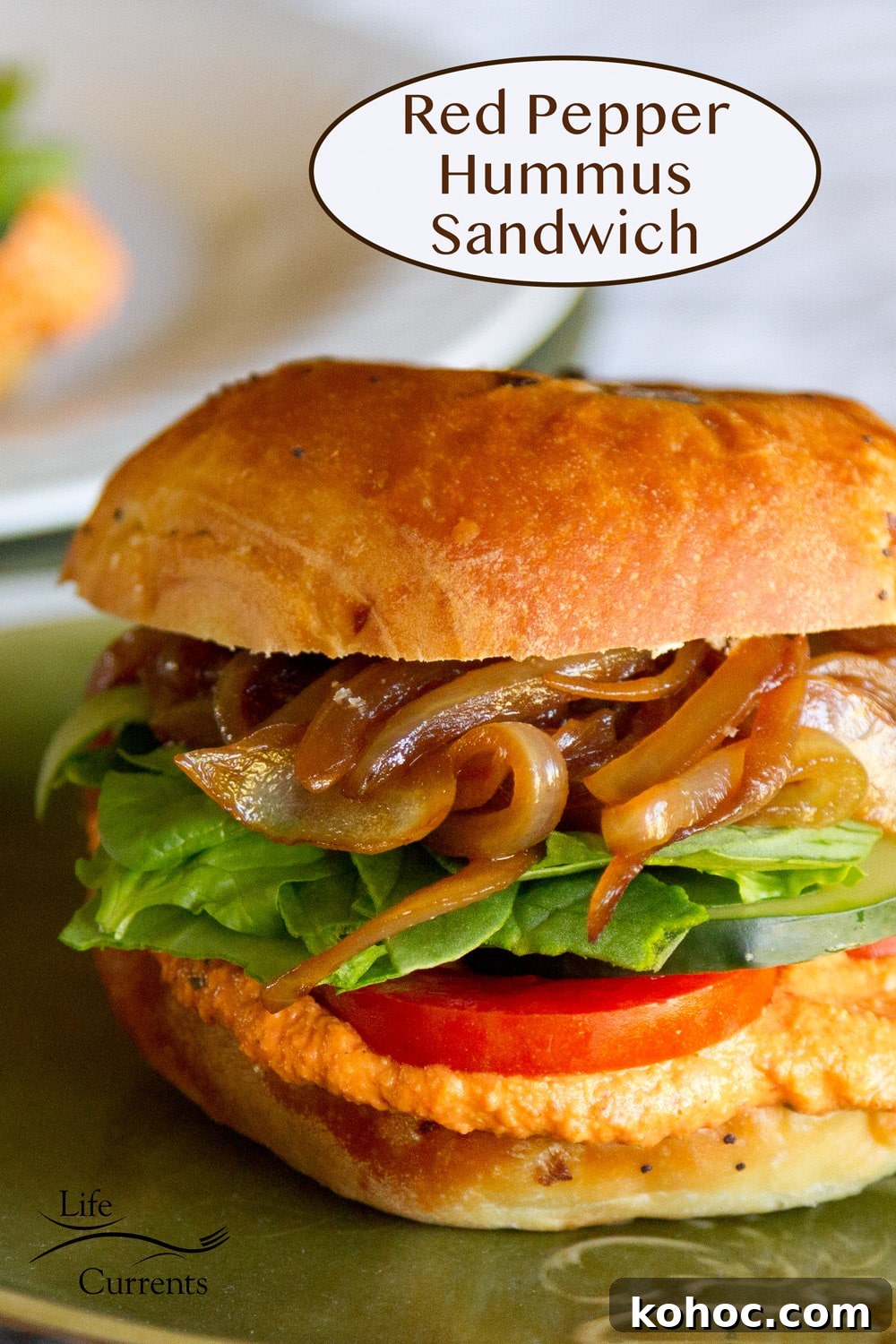 Roasted Red Pepper Hummus Sandwich Recipe for Flavorful Lunch 2 a red pepper hummus sandwich on onion bun with tomato, lettuce, and onions.