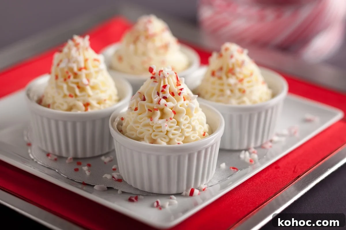 Silky White Chocolate Mousse Recipe: Step-by-Step Guide 3 Four white ramekins of white chocolate mousse topped with crushed peppermint candy garnish on a tray.
