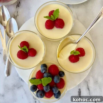 Four lemon posset custard dessert cups topped with fresh berries.