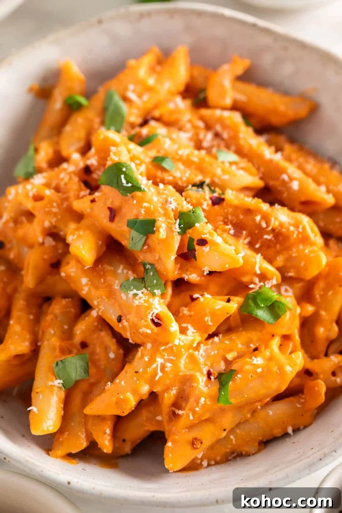 Penne with vegan pasta sauce in a bowl, topped with fresh basil and vegan Parmesan.