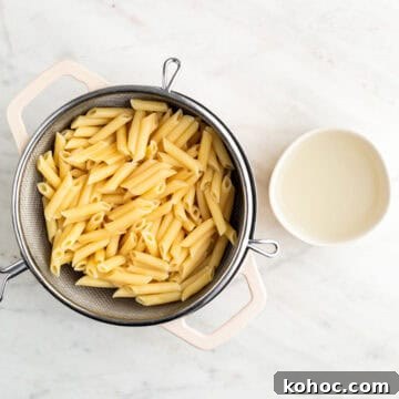 Cooked pasta in a pot and reserved pasta water in a bowl.