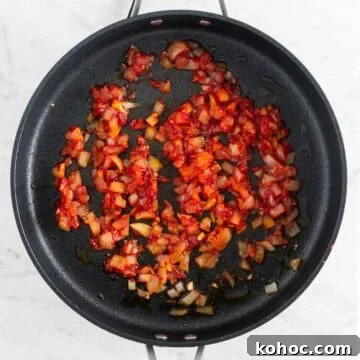 Sautéed onion and garlic with tomato paste, salt, pepper, and red pepper flakes in a skillet.