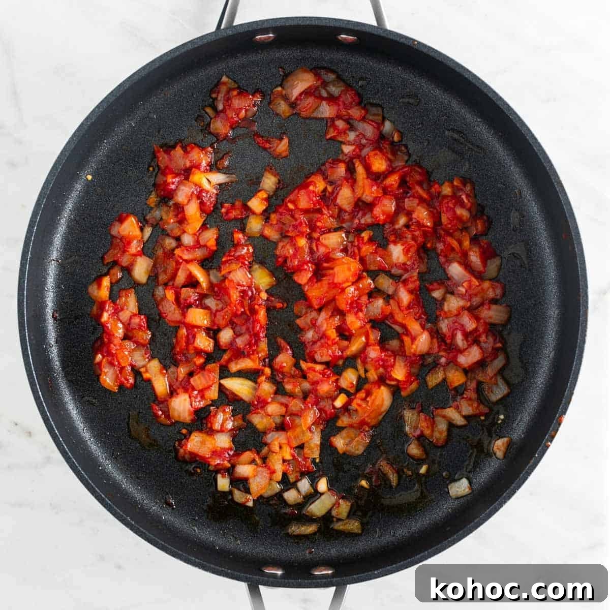 Sautéed onion and garlic with tomato paste, salt, pepper, and red pepper flakes in a skillet.