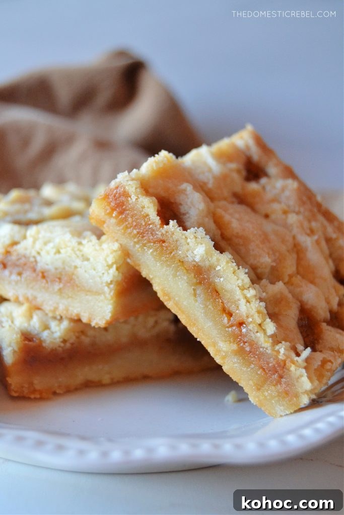 Salted Caramel Butter Bars Recipe with Buttery Shortbread Crust 5 three salted caramel butter bars sit on a small white plate.