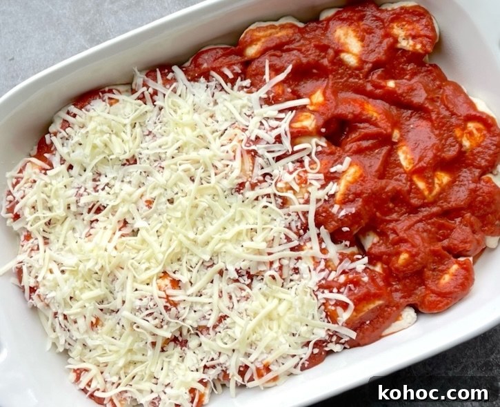 Bubble-Up Biscuit Pizza Casserole Recipe for Family Nights 7 A pizza casserole being prepared for the oven including quartered biscuit dough, sauce and shredded cheese.