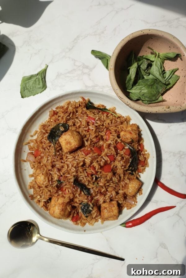 Thai basil fried rice on a plate with a spoon next to it.