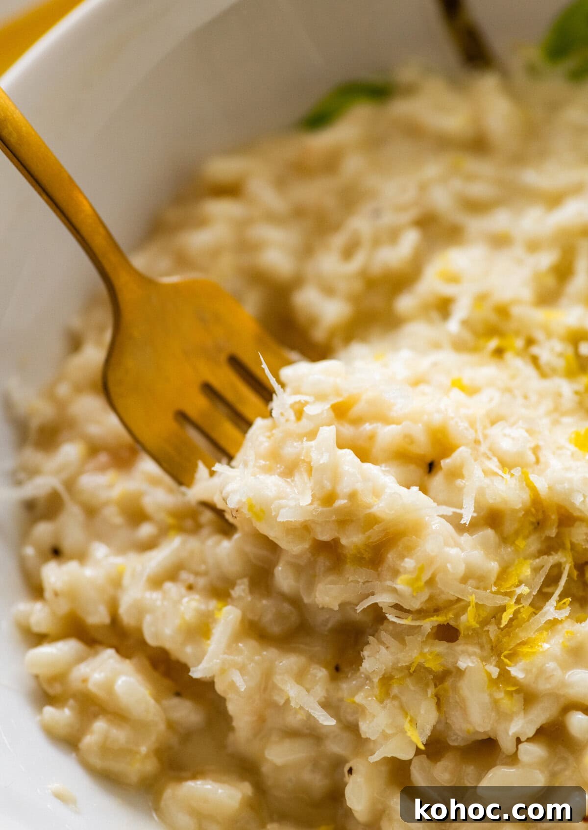 Creamy Lemon Risotto with Parmesan and Fresh Herbs 12 One bite of lemon risotto on a fork held over a bowl of more risotto.
