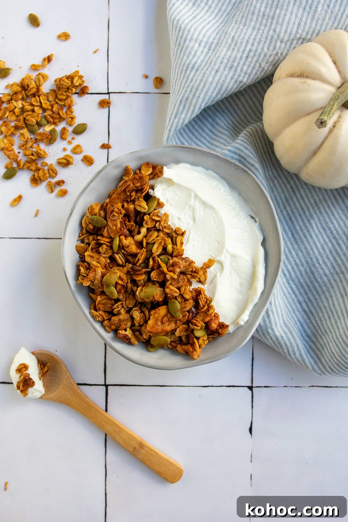 Pumpkin Granola with Maple or Date Syrup 2 Grey bowl with yogurt and granola, wooden spoon and striped linen napkin and white pumpkin.