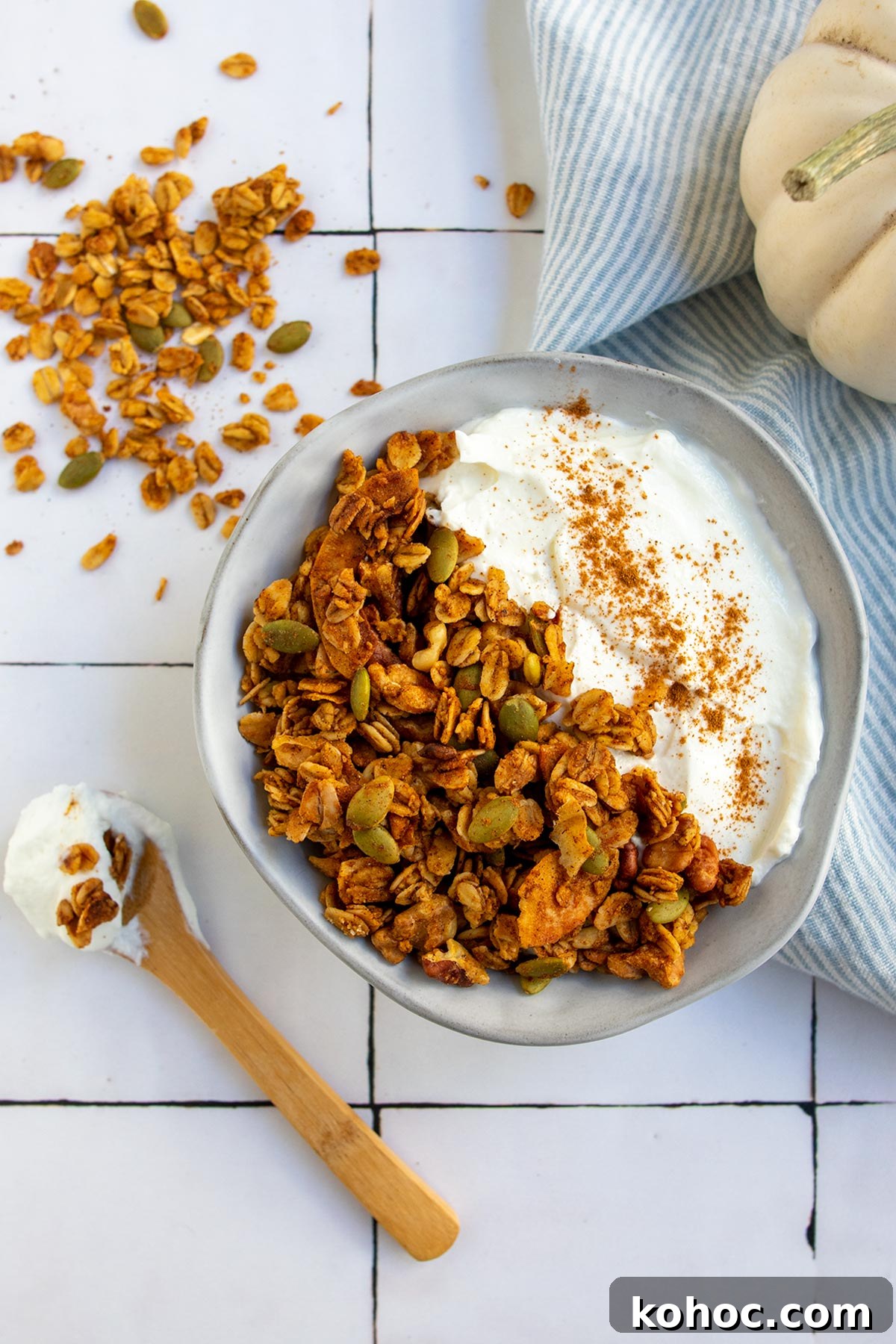 Pumpkin Granola with Maple or Date Syrup 11 A serving of granola in gray bowl with yogurt and cinnamon and a white pumpkin in the side.