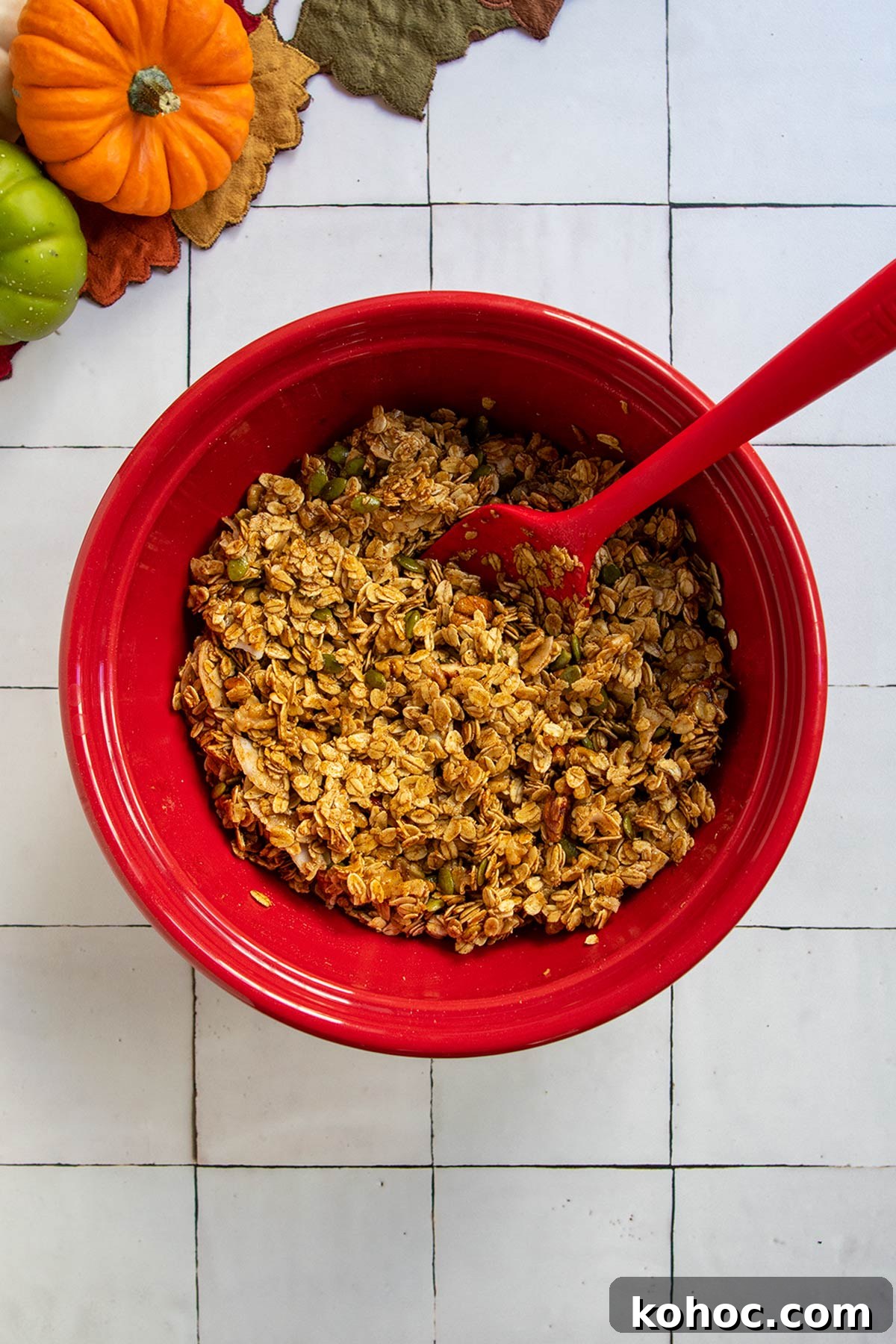 Pumpkin Granola with Maple or Date Syrup 8 Wet and dry pumpkin granola ingredients mixed together in red bowl with red rubber spatula.