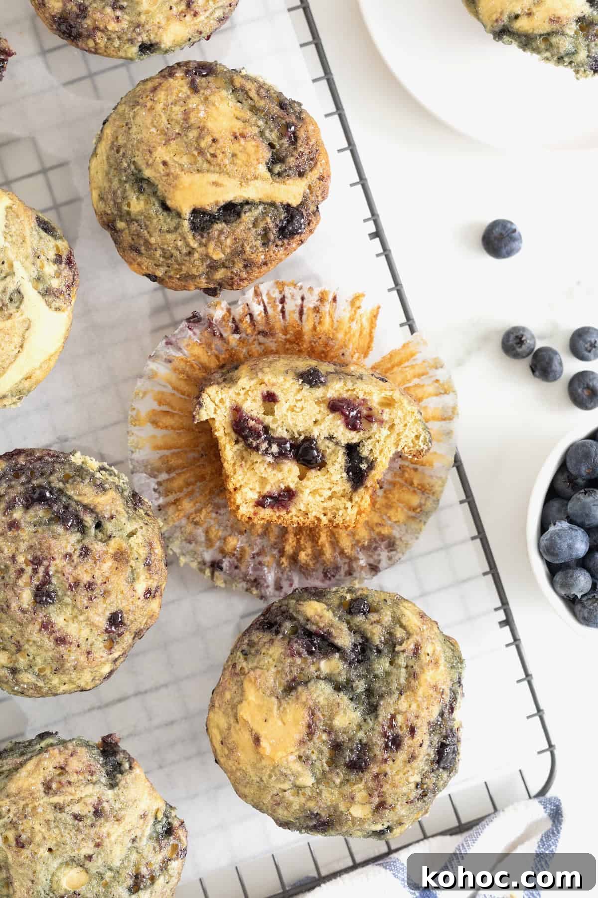 Six blueberry swirl muffins on a wire cooling rack. 