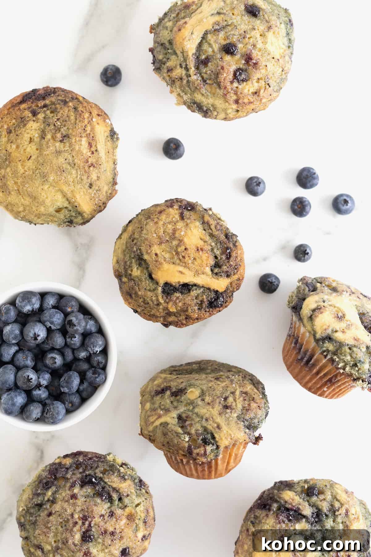 Blueberry swirled muffins on a white marble counter.