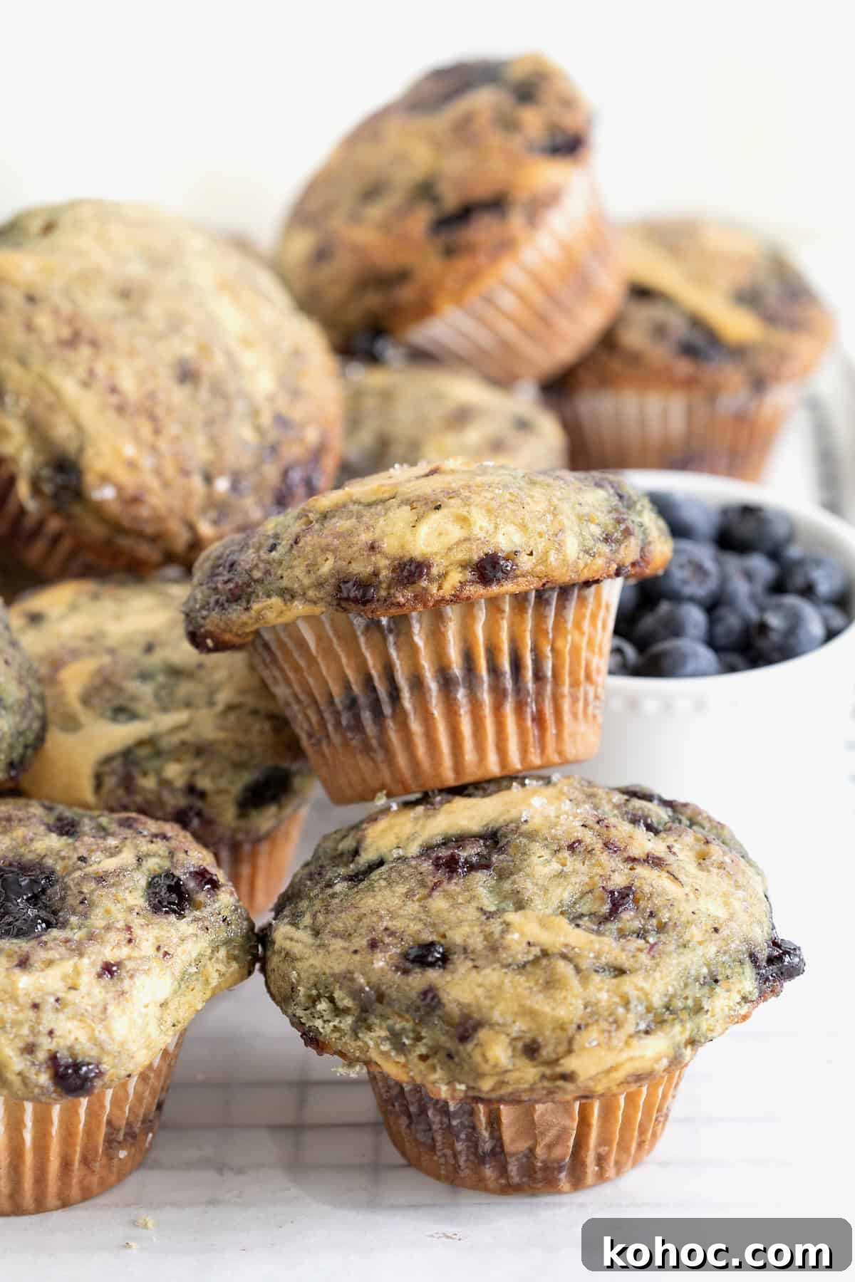 Piles of blueberry swirl muffins on a white surface.