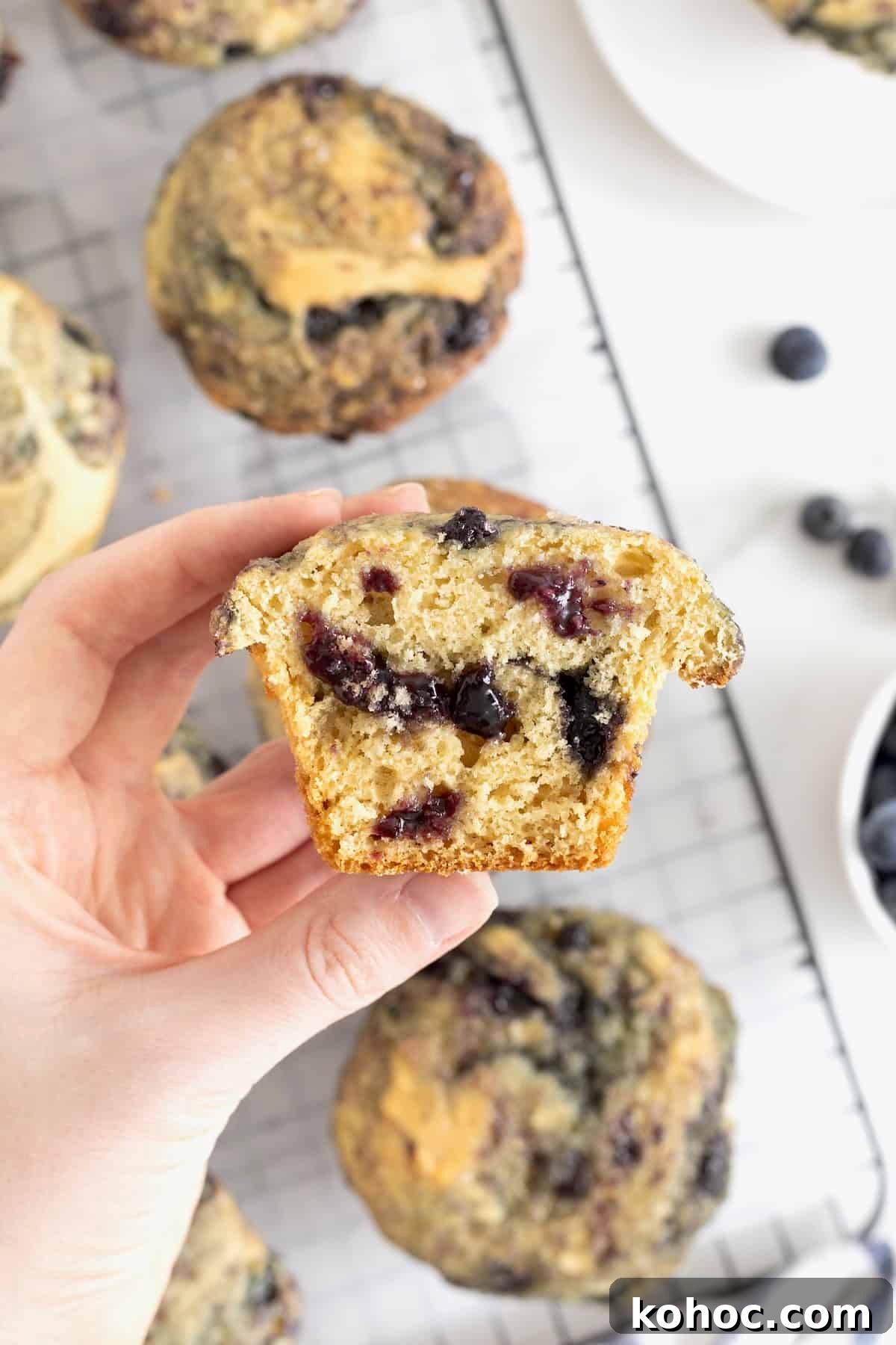 A hand holding a blueberry swirl muffin cut in half.