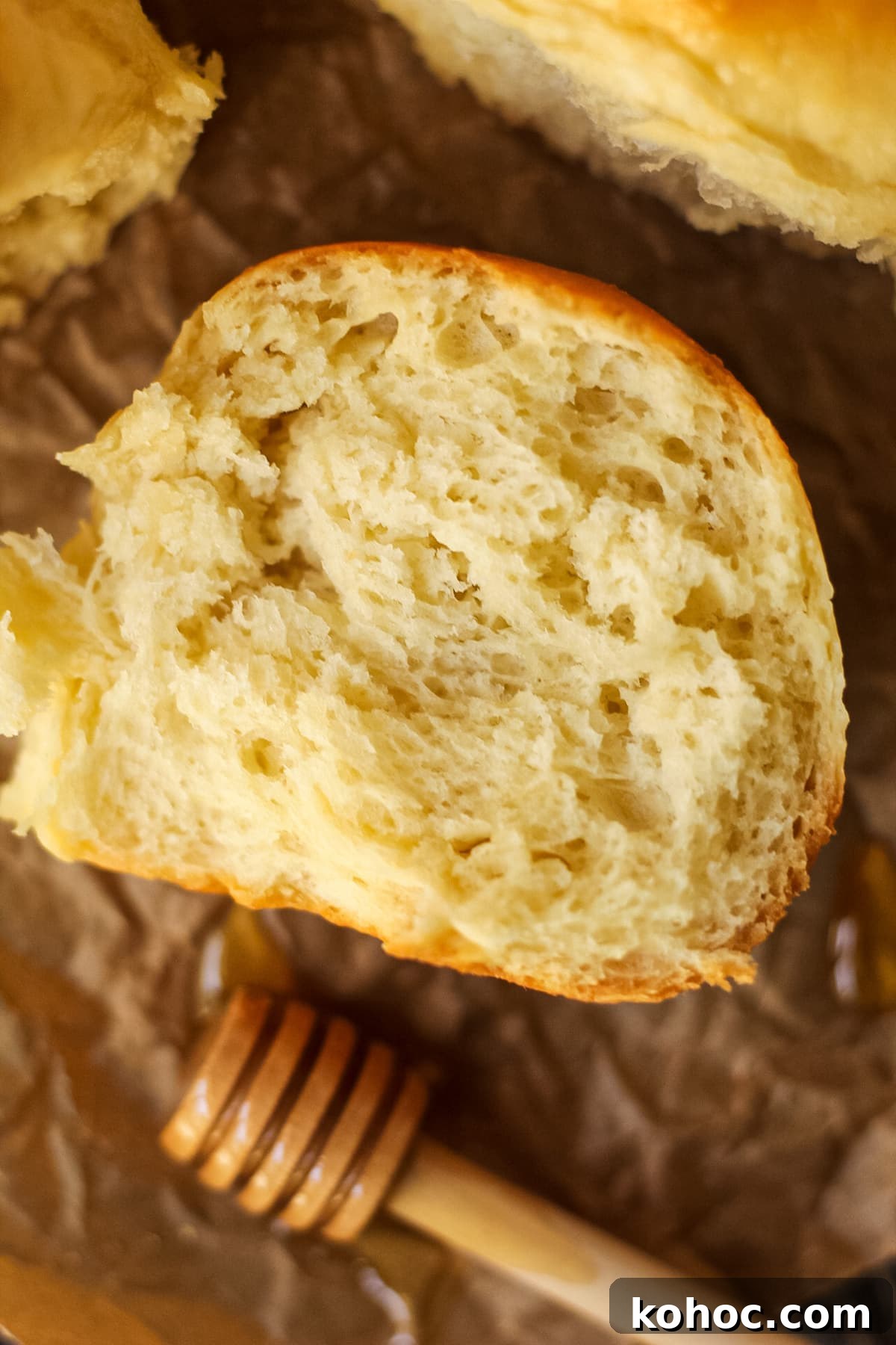 One-Hour Soft and Fluffy Dinner Rolls 9 honey butter dinner rolls on parchment paper. One roll torn open to show texture.