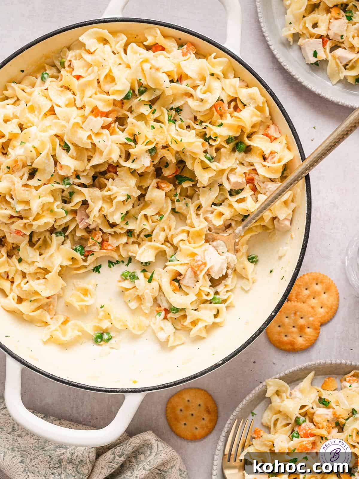 Made with seasoned chicken and egg noodles in a creamy sauce topped with Ritz crackers, Chicken Noodle Casserole is total comfort food. A wooden spoon stirring chicken noodle casserole