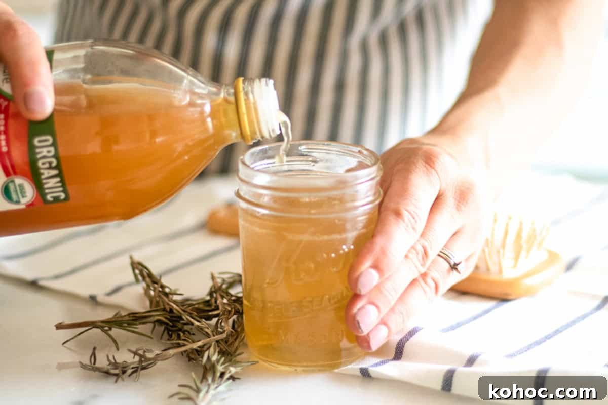 Pouring apple cider vinegar into a mason jar.