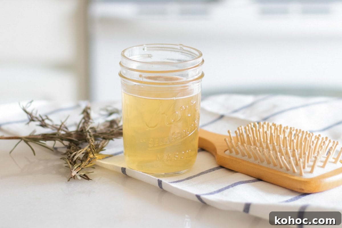 A jar of apple cider vinegar hair rinse with a hair brush and dried herbs.
