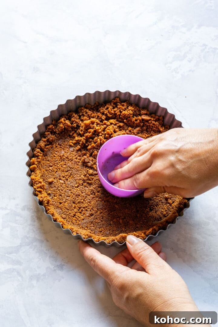 Decadent Chocolate Orange Tart Recipe with Zesty Ganache 5 Pressing cookie crumbs into a fluted tart pan.