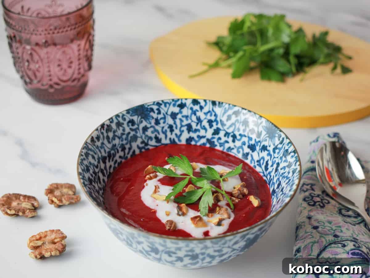 Roasted Beet and Walnut Soup Recipe — Comforting Autumn Starter 5 Bowl of Roasted Beetroot and Walnut Soup with coconut cream drizzle and walnuts and parsley sprinkled on top, with a chopping board of parsley in the background.