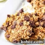 Side shot of multiple oatmeal cookies on a white rectangle plate.