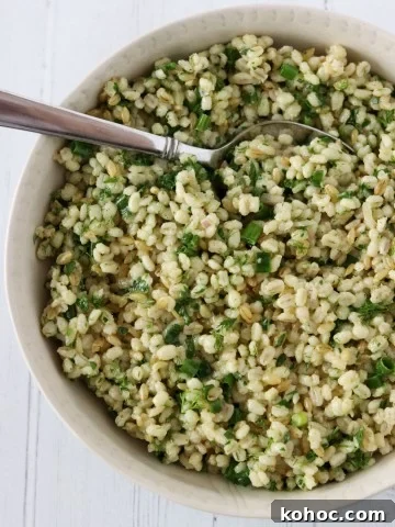Barley salad with fresh herbs in a bowl with a spoon