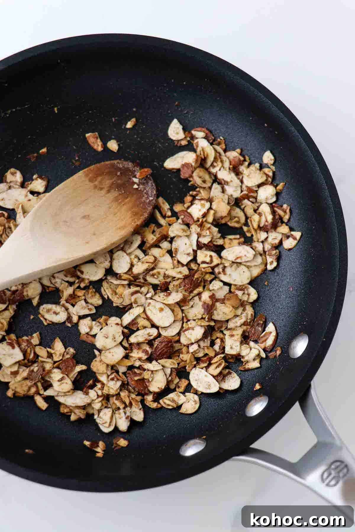 Hearty Savory Barley Breakfast Bowls for Morning Protein 5 Toasted spiced almonds in a skillet with a wooden spoon.