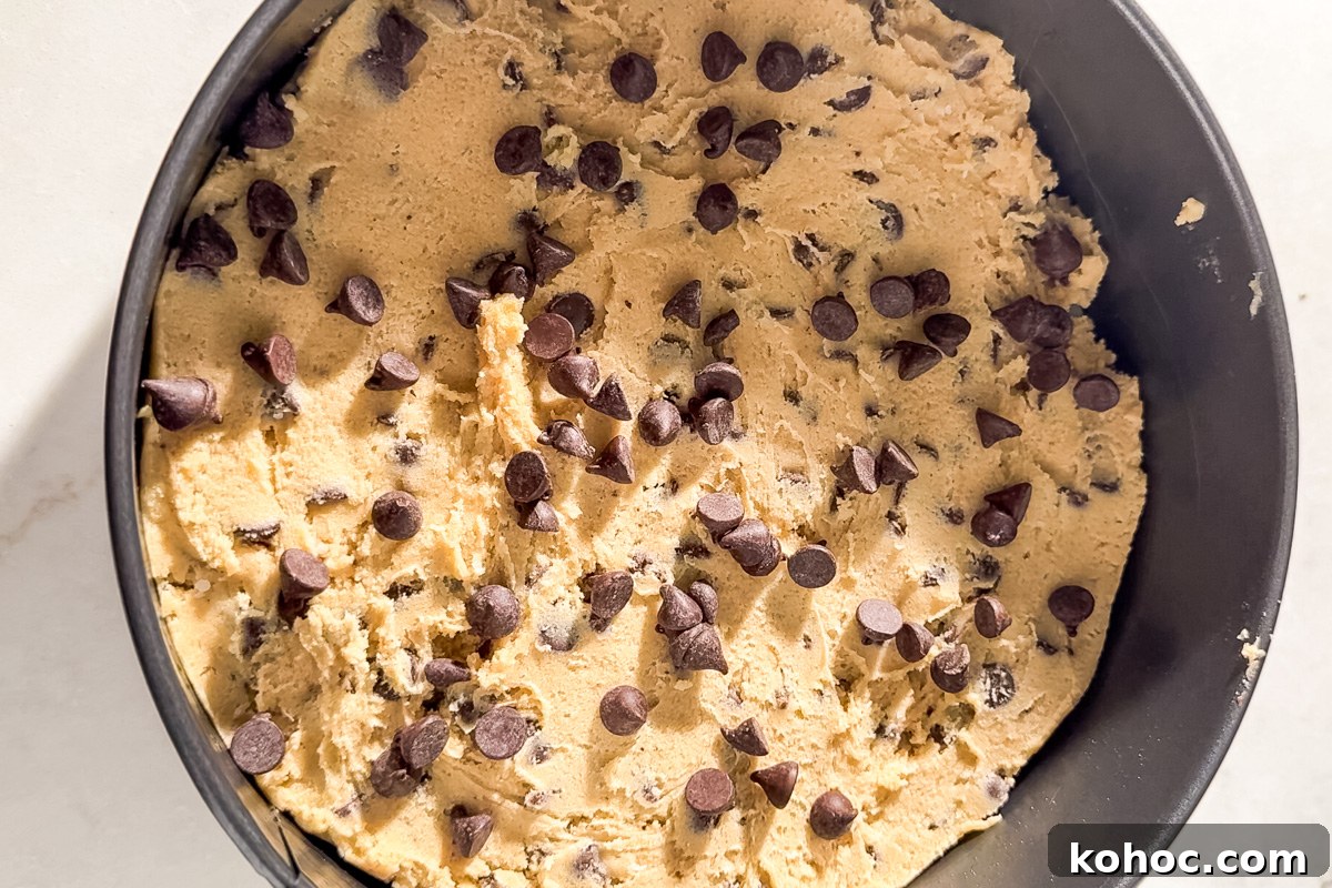 Gluten-Free Cookie Cake Recipe — Soft, Chewy Dessert Cake 12 Unbaked gluten-free chocolate chip cookie cake dough pressed into a round pan and topped with extra chocolate chips.