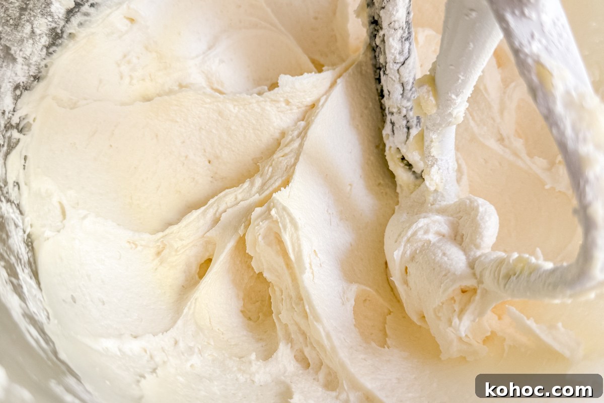 Gluten-Free Cookie Cake Recipe — Soft, Chewy Dessert Cake 15 Whipped vanilla buttercream frosting in a mixing bowl with a paddle attachment.
