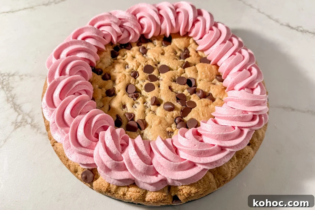 Gluten-Free Cookie Cake Recipe — Soft, Chewy Dessert Cake 16 Finished gluten-free cookie cake with a thick border of pink frosting swirls piped around the edge.