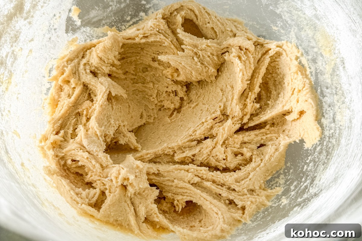 Gluten-Free Cookie Cake Recipe — Soft, Chewy Dessert Cake 10 Mixed cookie dough in a glass bowl before shaping, with a light and fluffy texture.