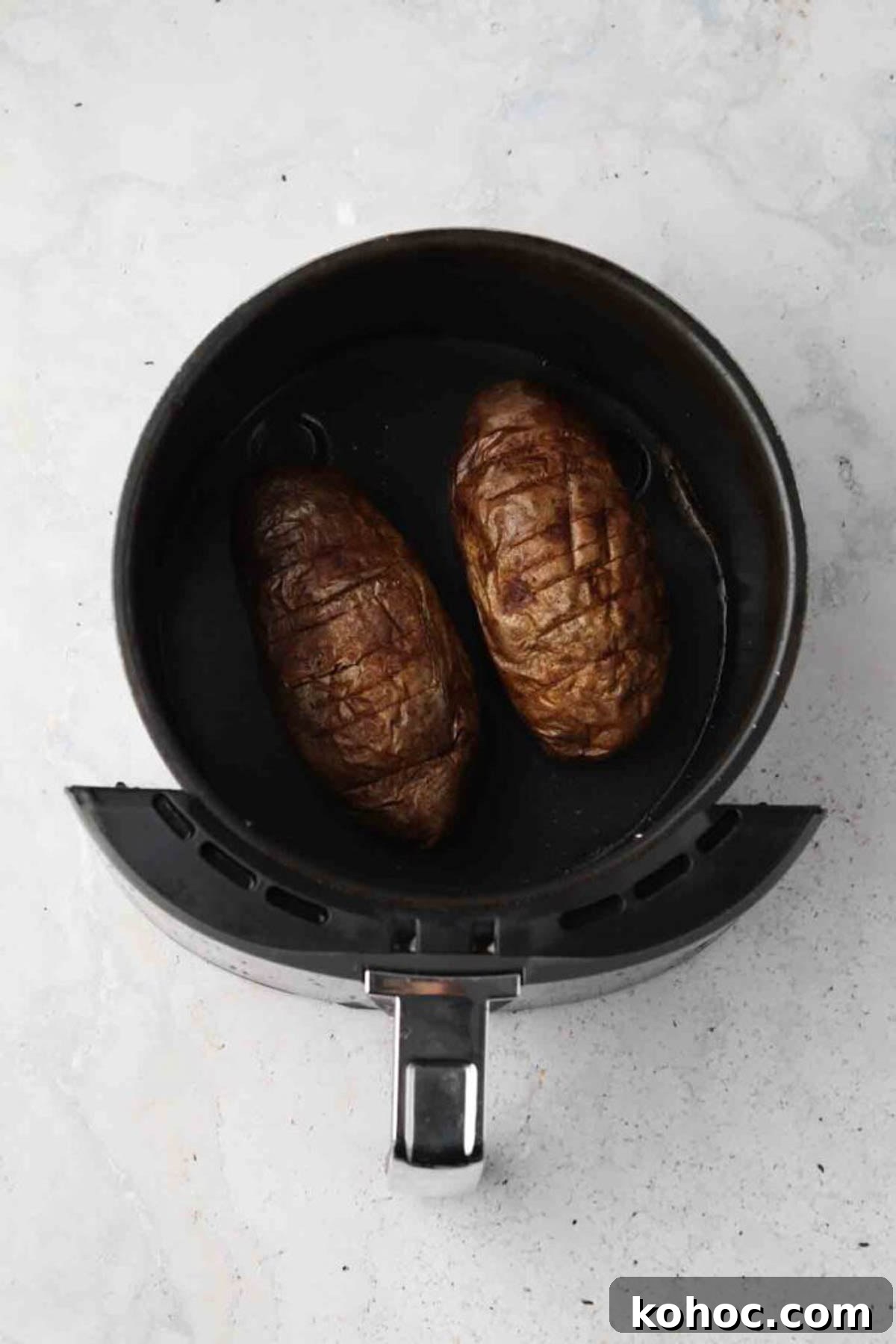 Crispy Air Fryer Potato Skins with Cheddar & Bacon 4 Two whole white potatoes uncooked in an air fryer basket.