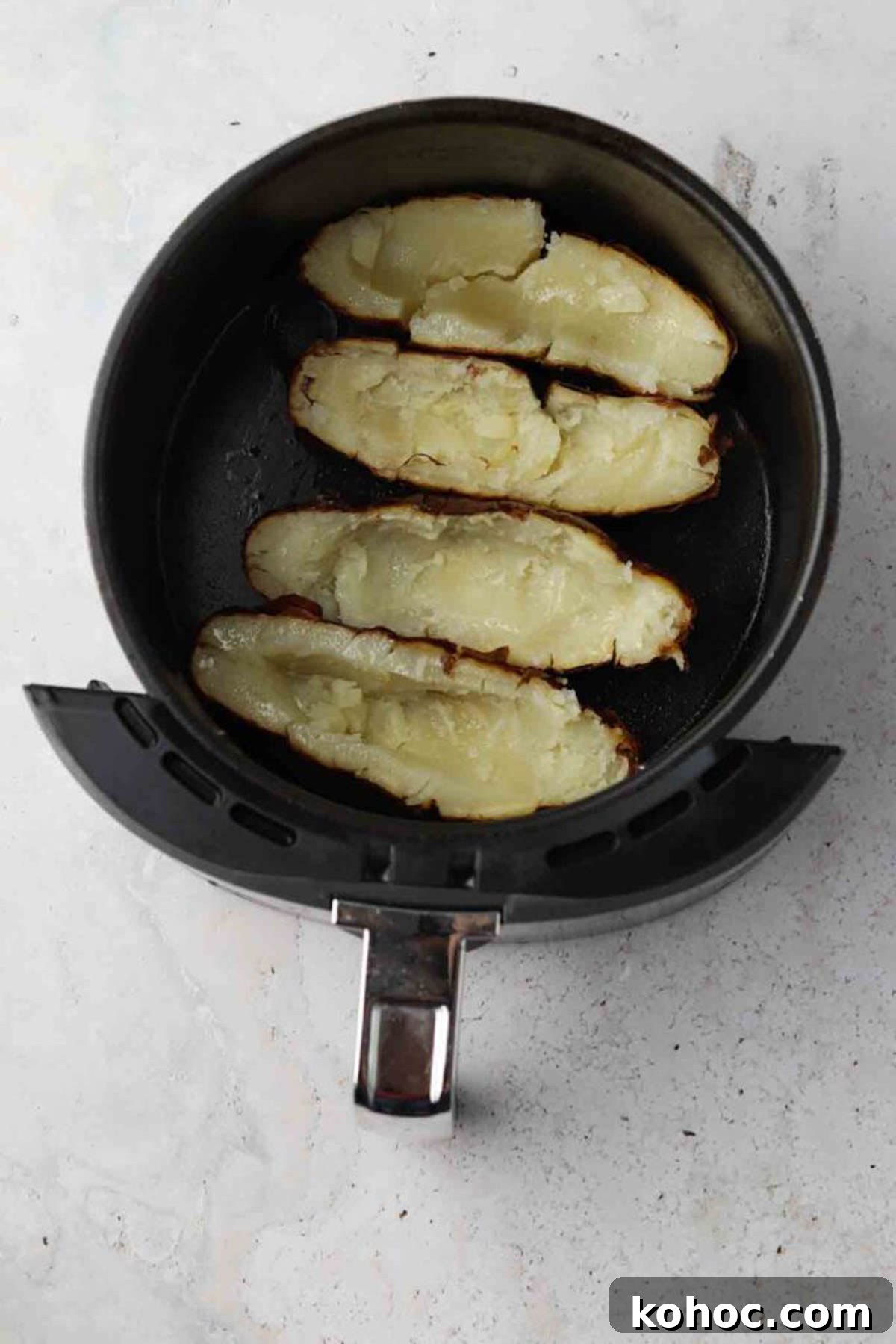Crispy Air Fryer Potato Skins with Cheddar & Bacon 5 Halved baked potato skins in an air fryer basket.